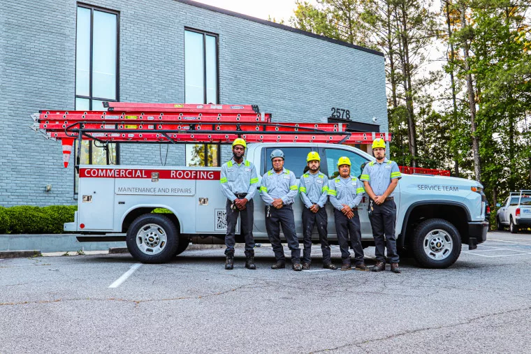 The Ideal Building Solutions commercial roofer team lined up in front of a work truck.